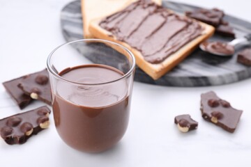 Tasty breakfast. Glass with sweet paste and chocolate pieces on white table, closeup