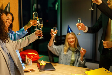 Multiracial young creative people are celebrating holiday in modern office. Group of young business people are drinking champagne in coworking