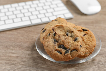Chocolate chip cookies on wooden table at workplace, closeup