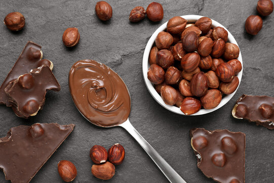 Spoon with tasty paste, chocolate pieces and nuts on grey table, flat lay