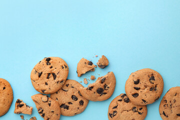 Many delicious chocolate chip cookies on light blue background, flat lay. Space for text