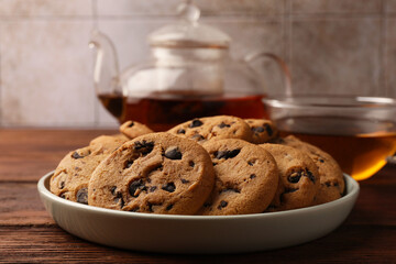 Delicious chocolate chip cookies and tea on wooden table, closeup