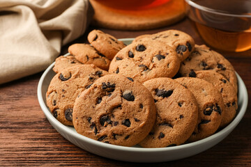 Delicious chocolate chip cookies and tea on wooden table, closeup
