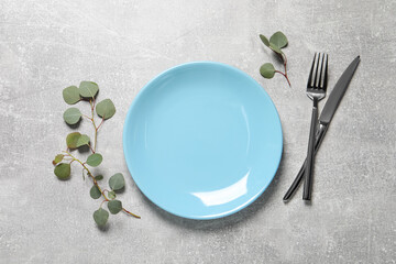 Stylish table setting with cutlery and eucalyptus leaves, flat lay