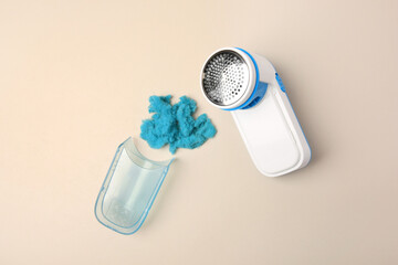 Disassembled fabric shaver with lint on beige background, flat lay