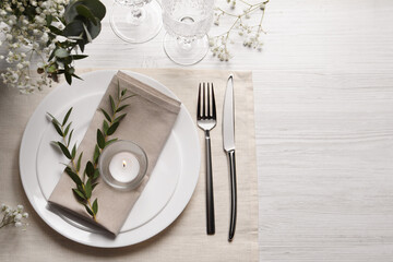 Stylish setting with cutlery and eucalyptus leaves on white wooden table, flat lay. Space for text