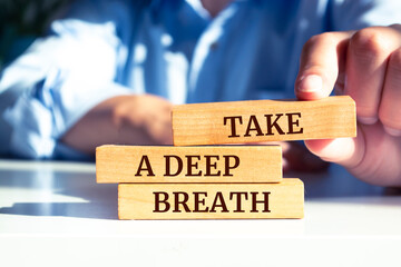 Close up on businessman holding a wooden block with "Take a Deep Breath" message