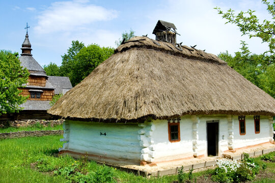 Traditional Ukrainian wooden hut (mazanka) with thatched roof in Pirogovo, Kev, Ukraine