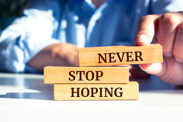 Close up on businessman holding a wooden block with "Never Stop Hoping" message