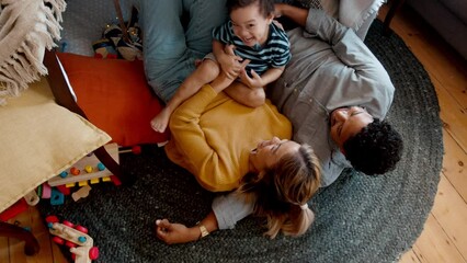 Happy boy laughing and enjoying himself as he gets tickled by his parents in a playful moment. Young family of three having fun and enjoying a leisure day at home. Son getting love and affection. - Powered by Adobe