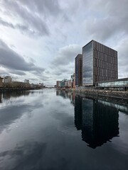 Fototapeta premium Modern buildings next to the river with reflections in the water. Salford Quays England. 