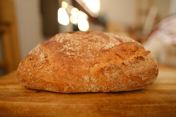 Big round appetizing fresh wholemeal bread with bran on wooden board, wheat, rye, multigrain bread, illuminated rays sun, concept bakery pastries, gluten products, diet, wholesome food, healthy eating