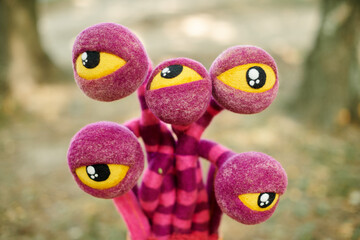 Purple striped flower with yellow eyes in clay pot on tree stump, strange crazy art object in...