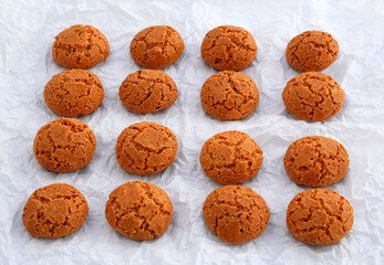 Traditional Italian almond cookies amaretti in a white handmade paper background.Famous amarettini cookie biscuits.Delicious Christmas pastry popular in Italy.Selective focus.