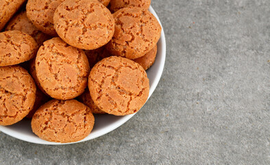 Traditional Italian almond cookies amaretti in a white plate on a gray background.Famous amarettini cookie biscuits.Delicious Christmas pastry.
Selective focus.