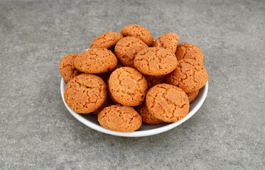 Traditional Italian almond cookies amaretti in a white plate on a gray background.Famous amarettini cookie biscuits.Delicious Christmas pastry.
Selective focus.