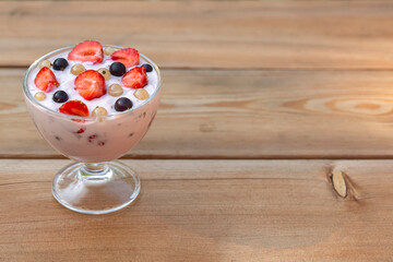 Yogurt with summer berries on a wooden table. Healthy food rich in fiber, vitamins and antioxidants.