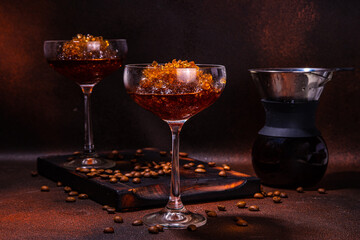 Espresso coffee slush cocktail in martini glass, with craft drips coffee maker. Hard coffee granita, on dark brown background copy space