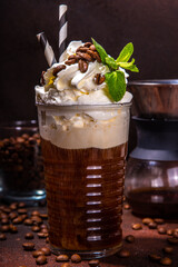 Iced coffee in tall glass. One sweet cold latte with whipped cream, with chemex coffee maker on dark brown background copy space