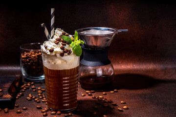 Iced coffee in tall glass. One sweet cold latte with whipped cream, with chemex coffee maker on dark brown background copy space