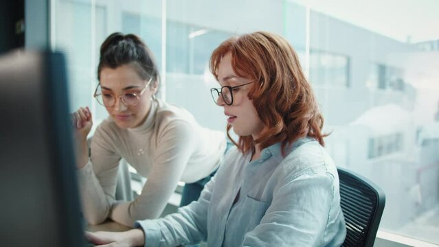 Women having a discussion while working on a programming code. Business women doing a software developing project in an office. Female professionals women working in a tech.