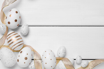 Flat lay composition with festively decorated Easter eggs on white wooden table. Space for text
