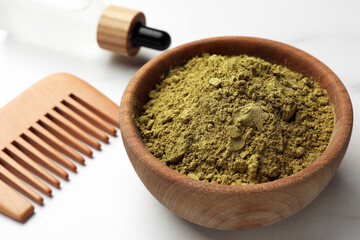 Bowl of henna powder, pipette and comb on white marble table