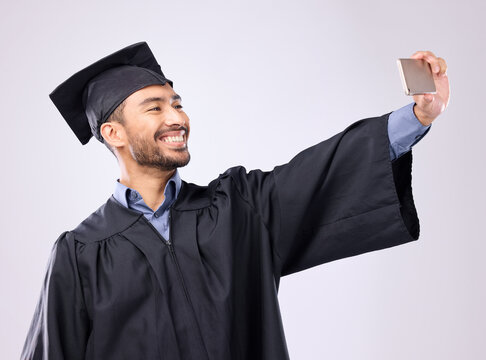 Man, graduate and selfie with smile for scholarship, profile picture or social media against a gray studio background. Happy excited male academic smiling for graduation photo, memory or online post