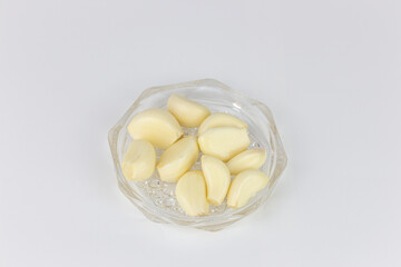 Garlic cloves in glass bowl isolated on white background, top view