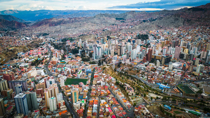 Aerial Drone Fly Above La Paz, Bolivia,  Crowder Metropolitan City, Houses, Skyscrapers and Andean Cordillera Mountain Range in the Background - obrazy, fototapety, plakaty
