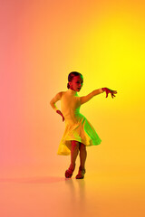 Elegant little girl in adorable stage outfit, dress dancing ballroom dance over gradient...