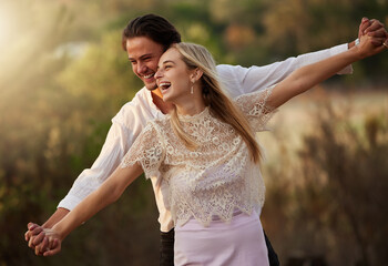 Happy, love and couple laugh in nature at sunset for romance, bonding and quality time together....