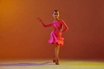 Studio shot of little girl, 11 years old kid in festive stage dress dancing ballroom dance over...