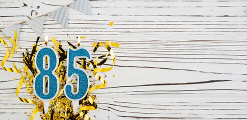 Number 85 blue celebration candle on white wooden background. Happy birthday candles. Concept of celebrating birthday, anniversary, important date, holiday. Copy space.