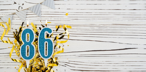 Number 86 blue celebration candle on white wooden background. Happy birthday candles. Concept of celebrating birthday, anniversary, important date, holiday. Copy space.
