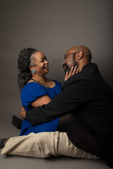 Studio portrait of an attractive middle aged black married couple. They are embracing and smiling. 