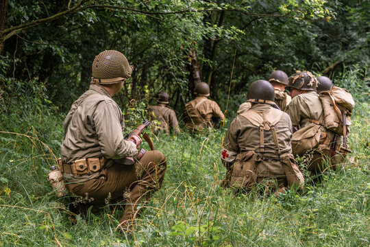 Historical reeneactors dressed As  american  Infantry Soldier during  World War II  patrol the forest. View from the back. Porąbka, Poland