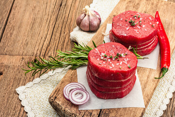 Raw Eye of round steak with spices and herbs on wooden background. Fresh meat for cooking food