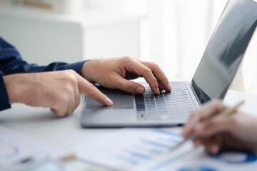 Person typing on laptop keyboard, businessman working on laptop, he is typing messages to colleagues and making financial information sheet to sum up the meeting.