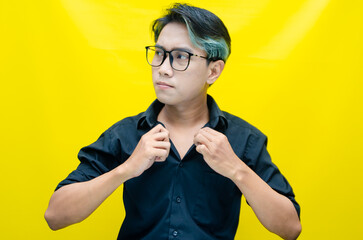 stressed, messed and depressed asian man in black shirt screaming madly and angrily isolated over yellow background.