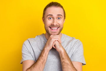 Portrait of optimistic guy dressed light t-shirt hold arms under chin excited waiting for shopping isolated on yellow color background
