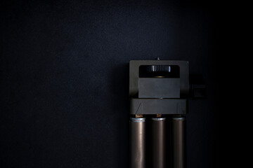 Beautiful old camera tripod on black background in dark room with studio lights