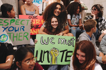 Happy teenage girls sitting with a crowd of climate activists