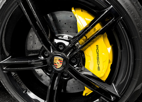 Yerevan, Armenia, March 15, 2023 : Front view of logo of Porsche Taycan on alloy wheel. Car exterior details. Tyre and alloy wheel with water drops. Carbon Ceramic brakes.