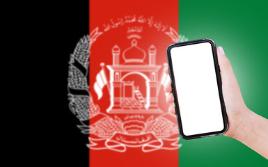 Male hand holding smartphone with blank on screen, on background of blurred flag of Afghanistan. Close-up view.