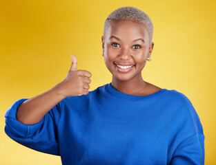Portrait, smile and black woman with thumbs up in studio isolated on a yellow background. Success,...