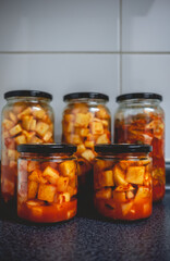 Details of spicy traditional kimchi in glass jars in kitchen (kimchi: mix of pickled and fermented vegetables like turnip or lettuce, garlic, chili peppers, salt)