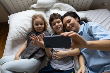 Happy caucasian mother and 2 kids have online video call with father or grandmother mobile phone...