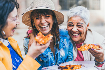 Women eating pizza outdoors at city - Happy three senior having fun together outside on street and laughing with food- Friendship and lifestyle concept