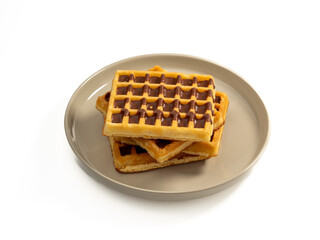 Chocolate waffles on a plate isolated on white background. Waffles in chocolate. Close-up.